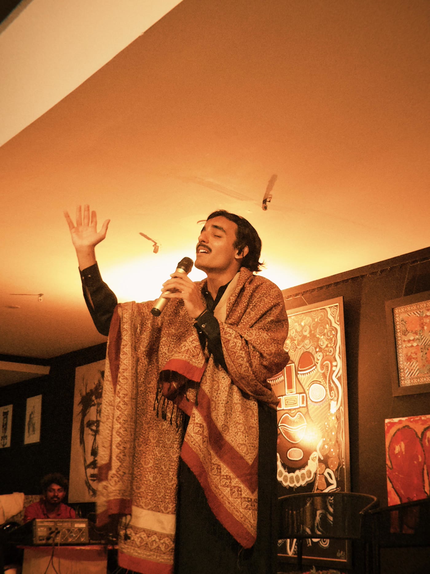 Mirza mid-performance, hand raised in song