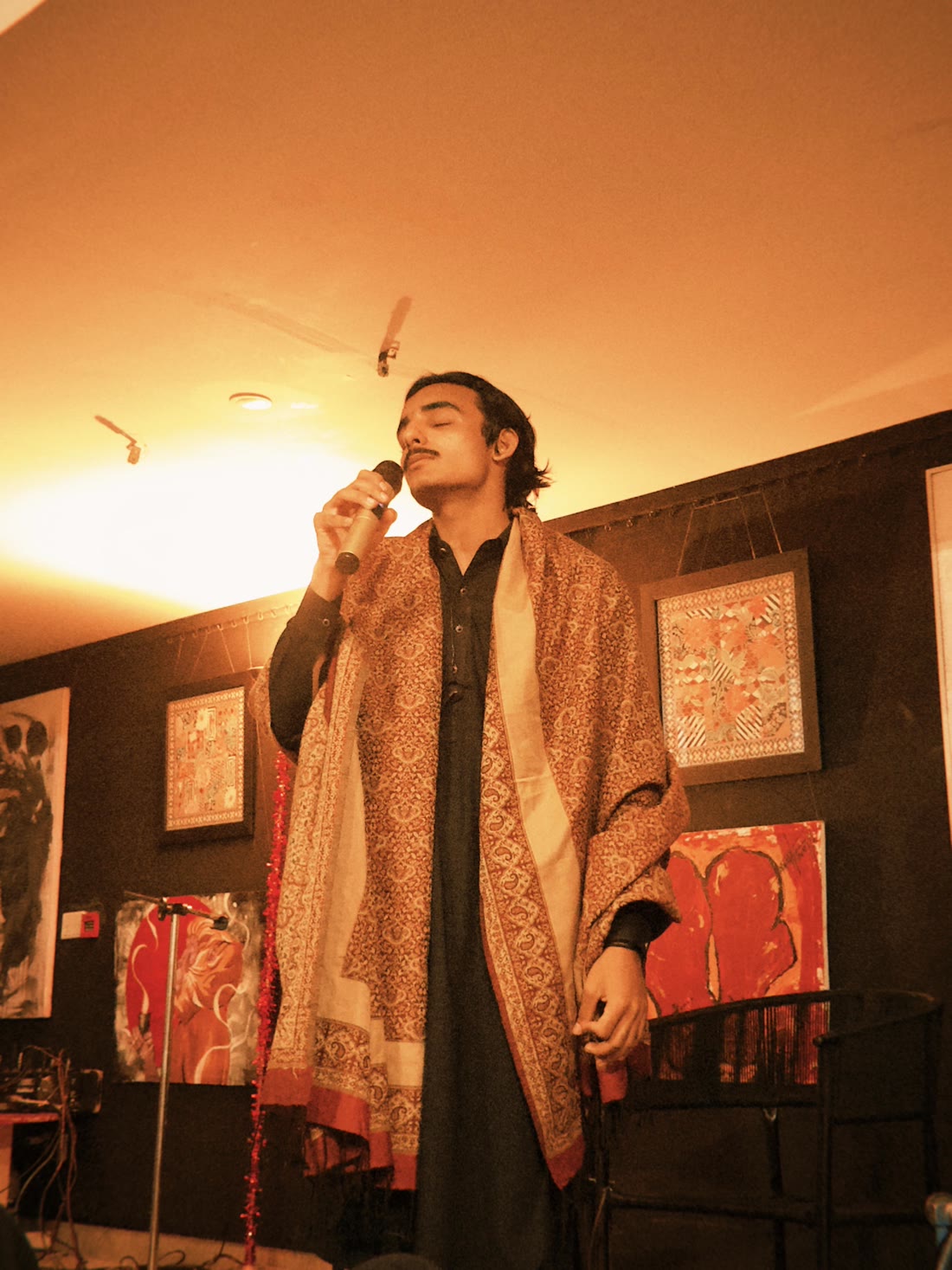 Mirza singing with eyes closed under warm light